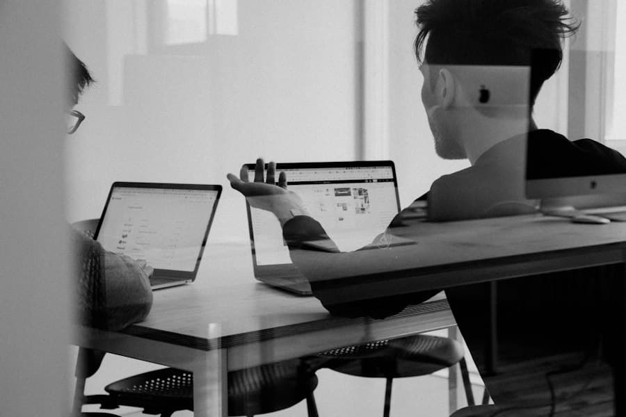 Colleagues discussing work across laptops at a table