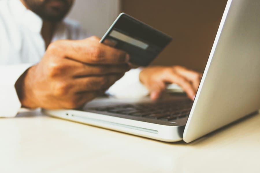 Hand holding a payment card while using a laptop