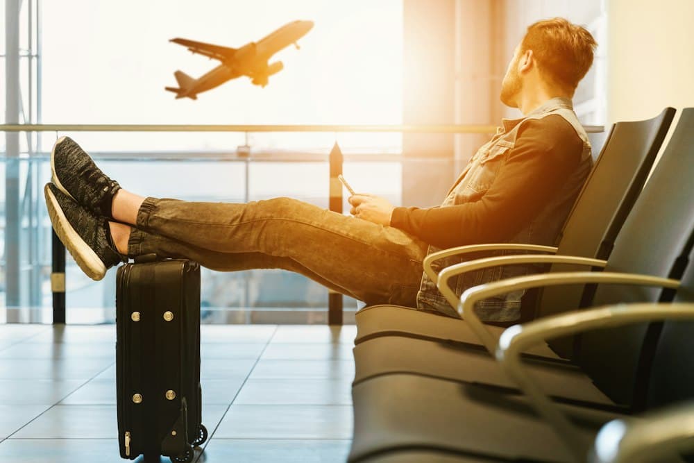 Traveller relaxing at an airport gate while a plane takes off